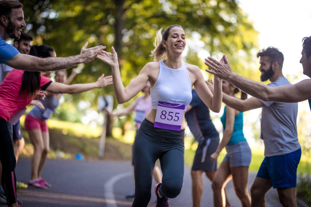 Young happy marathon runner greeting with group of supporters at finish line after the race.