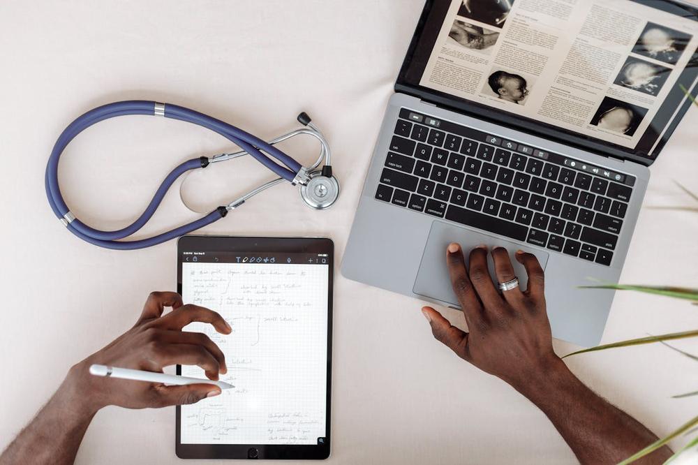 A doctor working on medical case with a laptop and tablet. 