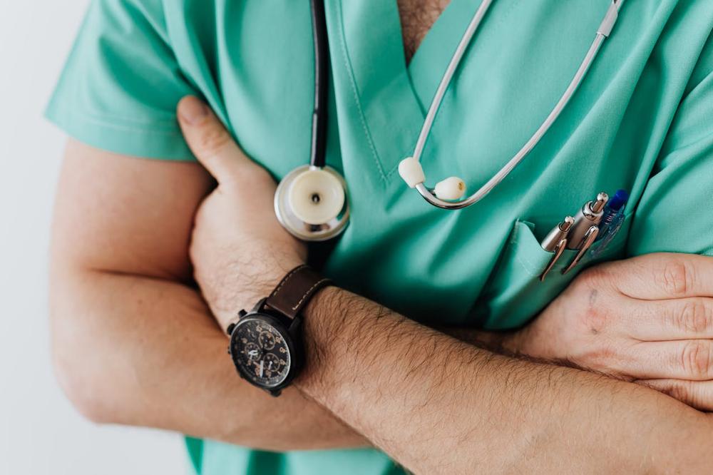 A doctor with crossed hands and medical equipment which shows what to expect when you answer the question why you should study medicine